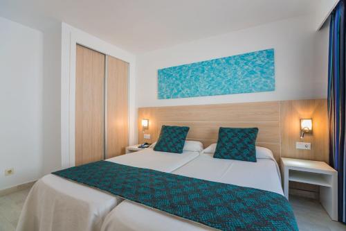 a bedroom with a large white bed with blue pillows at Aparthotel Holiday Center in Santa Ponsa