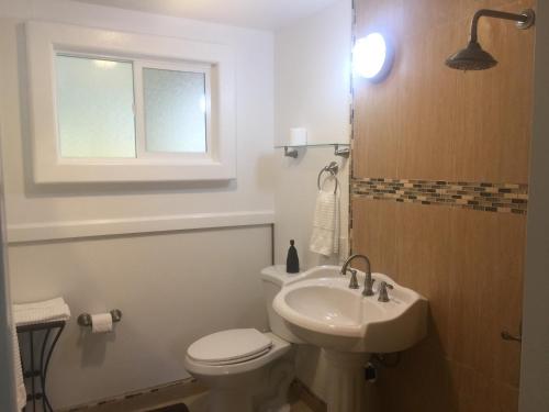 a bathroom with a toilet and a sink and a window at Aaron’s cottage in Hilo