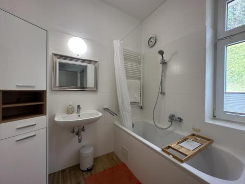 La salle de bains blanche est pourvue d'une baignoire et d'un lavabo. dans l'établissement Zum Radwerk TOP 11, à Vordernberg