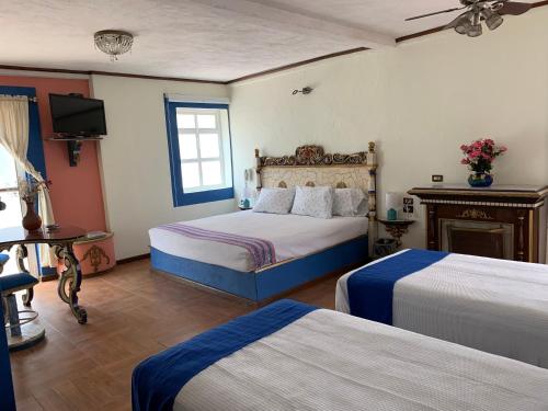 Habitación de hotel con 2 camas y TV en Mesón Yollotl, en Puebla