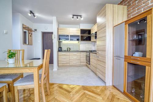 - une cuisine avec des placards en bois et une table à manger dans l'établissement Apartament Mokotów Wierzbno, à Varsovie