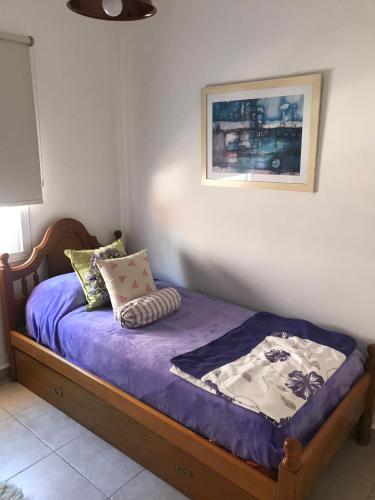 a bedroom with a bed with purple sheets and pillows at Complejo Los Aromitos 1 in Río Ceballos