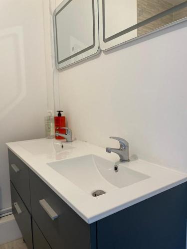 La salle de bains est pourvue d'un lavabo blanc et d'un miroir. dans l'établissement Calme et confort: Appartement 3 chambres + balcon, à Bourges