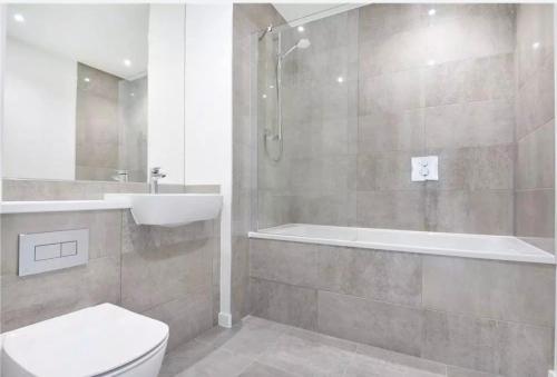 a bathroom with a toilet and a sink and a tub at Canary Wharf Luxury 2 Bed Apartment in London
