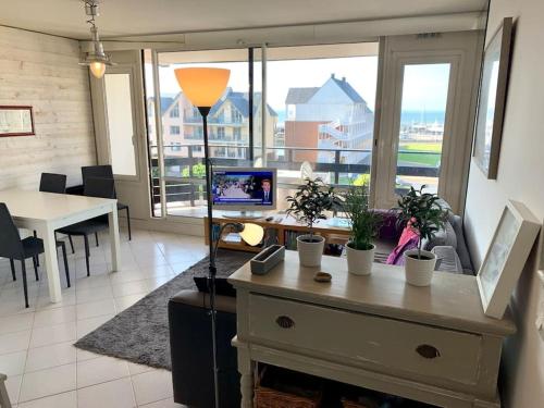 un salon avec une table et une grande fenêtre dans l'établissement Bel appartement vue mer avec parking gratuit, à Deauville