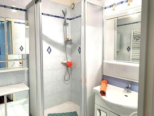 une salle de bain blanche avec une douche et un lavabo dans l'établissement Bel appartement vue mer avec parking gratuit, à Deauville