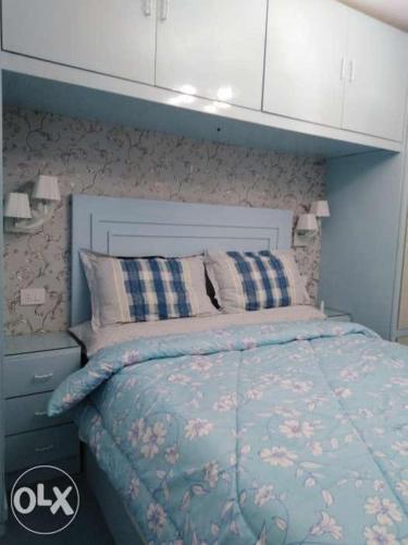 een slaapkamer met een bed met een blauw dekbed bij شقه للإيجار المفروش سوبر لوكس (vip) أمام البحر مباشرة in Alexandrië