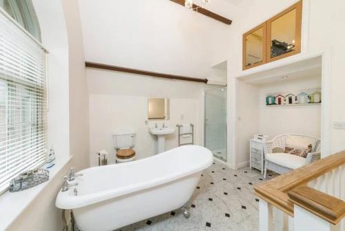 La salle de bains est pourvue d'une grande baignoire blanche et d'un lavabo. dans l'établissement Folly - Middleton Hall Estate, à Belford