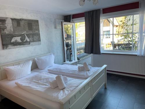 1 dormitorio con 1 cama con sábanas y almohadas blancas en Trattoria & Apartments - Casa da Enzo, en Goslar