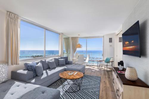 a living room with a blue couch and large windows at Ilikai Collection 12 Corner Oceanfront Condo with amazing views in Honolulu