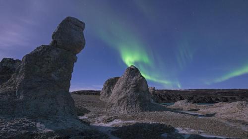 an image of the aurora dancing in the sky over rocks at Rivdnji Holiday Home Smørfjord in Russenes
