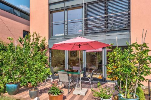 a table with a red umbrella in front of a building at Splendido attico per chi ama escursioni nella natura in Grono