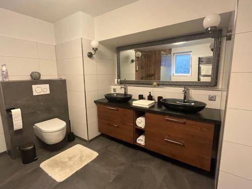 a bathroom with two sinks and a toilet and a mirror at Wormis Apartment Heideblick bei Luckau in Heideblick