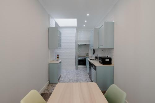 a kitchen with white cabinets and a wooden table at Casa do Azulejo II in Setúbal