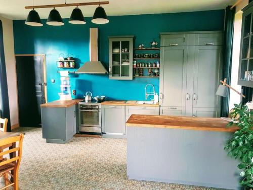 cocina con paredes azules, armarios blancos y encimera en Chambre spacieuse avec vue sur clocher, en Verchin