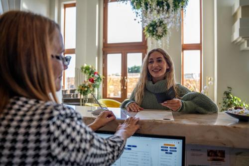 two women sitting at a table with a computer at Santa Lucia Boutique Hotel in Santa Luċija