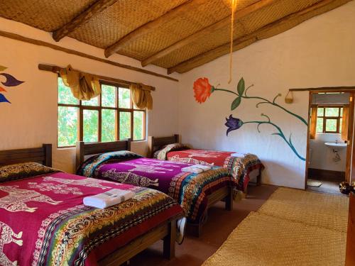 3 Betten in einem Zimmer mit Wandgemälde in der Unterkunft PONDOWASI LODGE in Ibarra