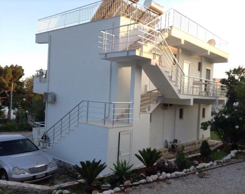 a white house with stairs and a car parked in front at Guest house Plazhi Dhermi in Dhërmi