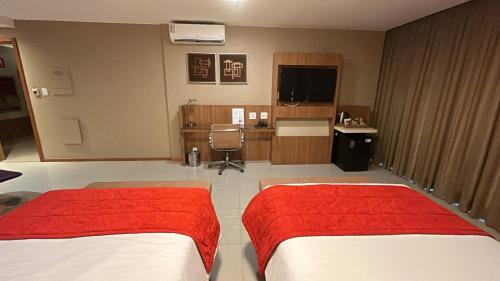 a hotel room with two beds and a desk at Jade Hotel Brasília in Brasilia