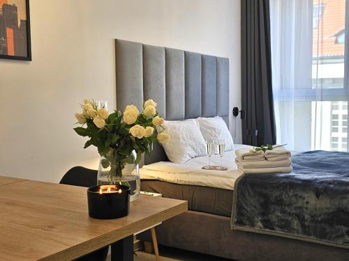 a bedroom with a bed with a vase of flowers on a table at URBAN APARTMENTS PREMIUM, Opolska 10 No 77B, Free Garage, Self Check-in in Katowice