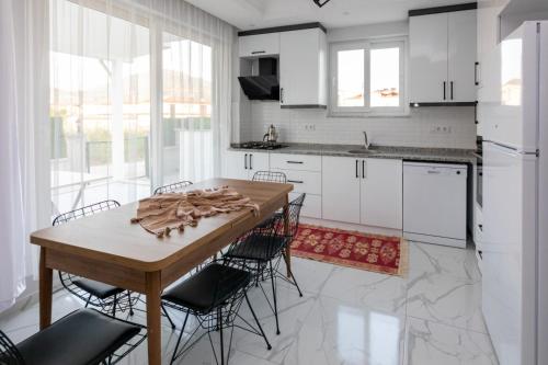 a kitchen with white cabinets and a wooden table and chairs at Lavender Villas in Dalaman