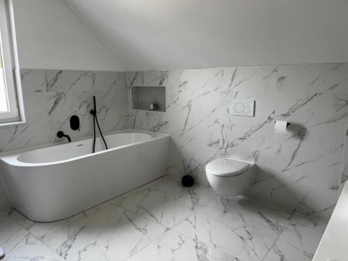 uma casa de banho branca com uma banheira e um WC em Hochwertiges Haus mit Garten mit guter Anbindung em Berlim