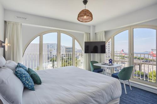 a bedroom with a large bed and large windows at Odalys City Marseille Centre Euromed in Marseille