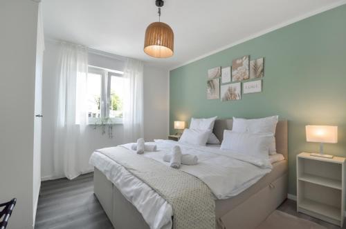 ein Schlafzimmer mit einem großen weißen Bett mit zwei ausgestopften Tieren in der Unterkunft Stilvolle Stadtoase - Balkon - Parkplatz in Steinhagen