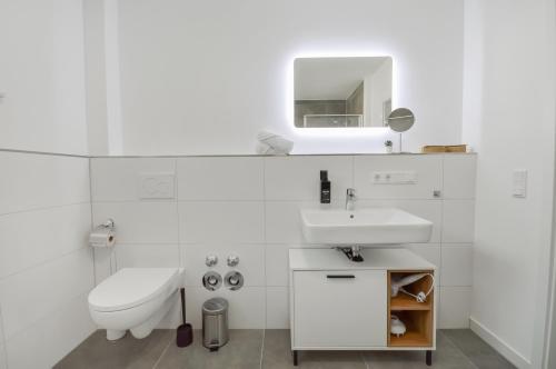 ein weißes Bad mit einem Waschbecken und einem WC in der Unterkunft Stilvolle Stadtoase - Balkon - Parkplatz in Steinhagen