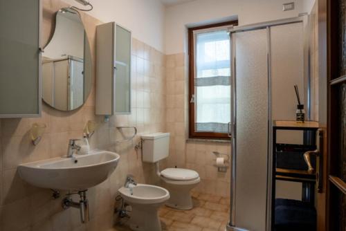 ein Badezimmer mit einem Waschbecken, einem WC und einem Spiegel in der Unterkunft VIVI SERENO, uno stile si vita! in Grosio