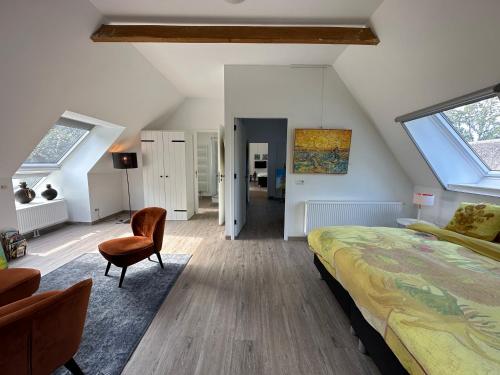 1 dormitorio en el ático con 1 cama y 1 silla en Galerie23noordsleen, en Noord-Sleen