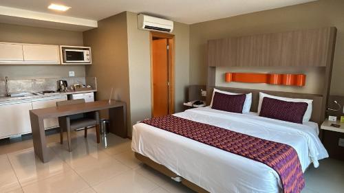 a bedroom with a bed and a desk and a kitchen at Jade Hotel Brasília in Brasilia