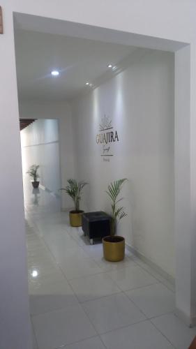 un hall avec des plantes en pot et un panneau sur le mur dans l'établissement Guajira Sunset Hostal, à Ríohacha