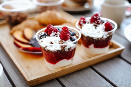 two cups of dessert on a wooden tray with fruit at Holiday House Sunset Spa in Šentjernej