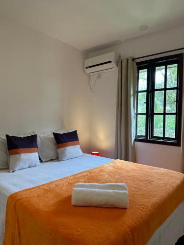 a bedroom with a large bed with an orange blanket at Pousada Sambaki in Paraty