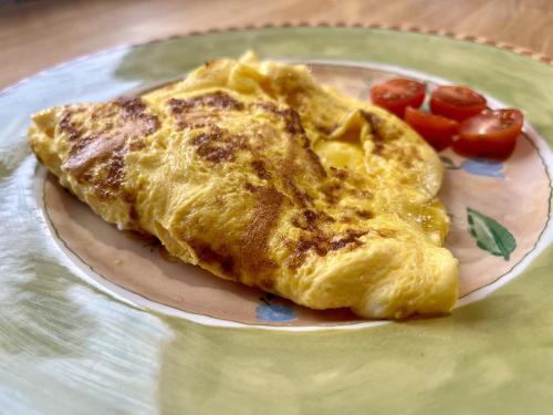 a plate of omelet and tomatoes on a table at Priors Oak - A Cosy Studio with Countryside Views in Dorset in Stalbridge