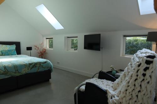 a bedroom with a bed and a chair and a tv at Galerie23noordsleen in Noord-Sleen