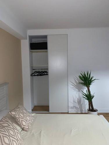 - une chambre avec un lit blanc et une plante en pot dans l'établissement Au Sunrise Studio, à Thonon-les-Bains