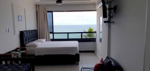 a bedroom with a bed and a view of the ocean at Farol Barra Flat in Salvador