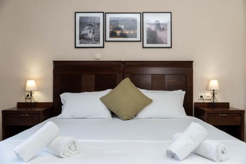 a bedroom with a large white bed with three pictures on the wall at Spilaio at Meteora in Kalabaka