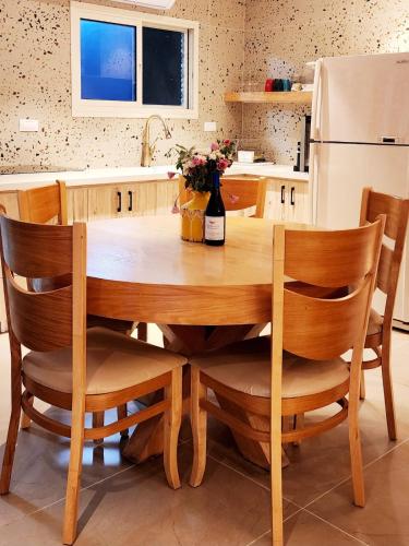 a kitchen with a wooden table with chairs and a refrigerator at Serentias suite & spa in Ein Kinya