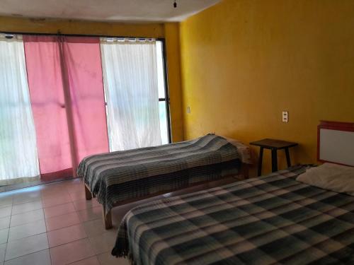 2 camas en una habitación con paredes y ventanas coloridas en Casa de campo, cerca del aeropuerto internacional del Vacío, en Guanajuato