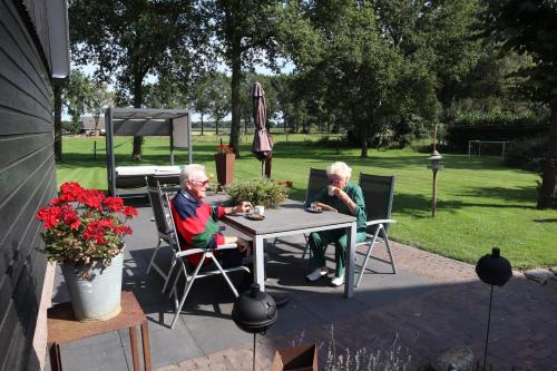 two older people sitting at a table in a yard at Galerie23noordsleen in Noord-Sleen