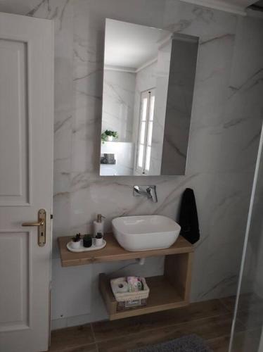 a white bathroom with a sink and a mirror at Ioannina Cozy Hill House in Pedini