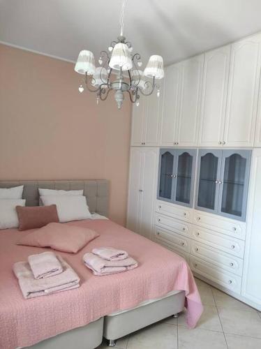 a bedroom with a bed with pink sheets and a chandelier at Ioannina Cozy Hill House in Pedini