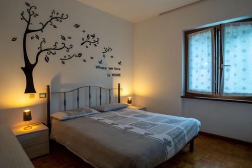 ein Schlafzimmer mit einem Bett mit einem Baum an der Wand in der Unterkunft VIVI SERENO, uno stile si vita! in Grosio