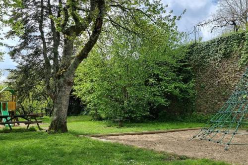 a tree and a bench next to a brick wall at Le Pavillon bleu Vouvant - Gite Maison in Vouvant