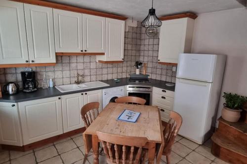 a kitchen with a wooden table and a white refrigerator at Le Pavillon bleu Vouvant - Gite Maison in Vouvant