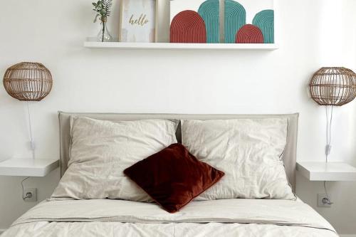 Una cama con una almohada roja encima. en Maison avec jardin proche de Paris, en Mormant