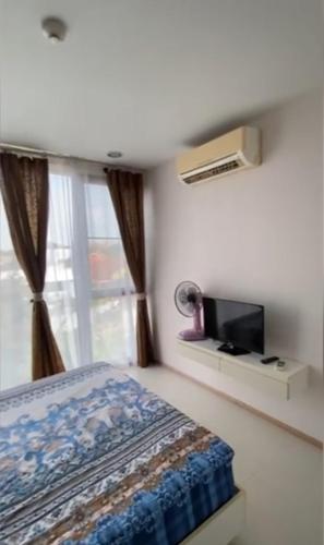 sypialnia z łóżkiem, telewizorem i oknem w obiekcie Acqua Apartment w mieście Jomtien Beach